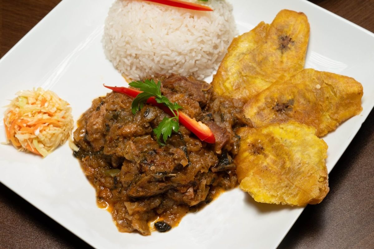 Haitian legim vegetable stew with white rice, fried plantains, and pikliz at Chez Le Bebe