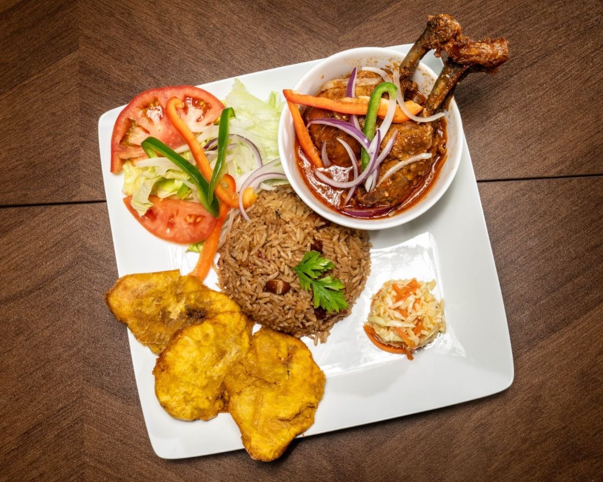 Haitian poulet en sauce, chicken in Creole sauce with rice, fried plantains, and pikliz